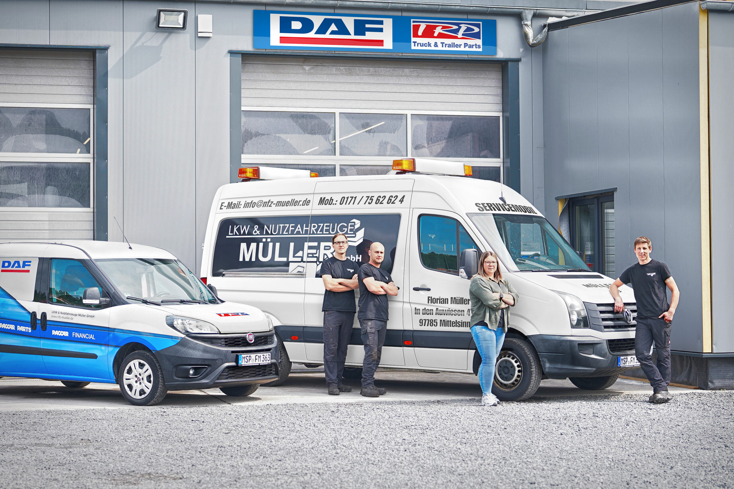 2 Fahrzeuge und Mitarbeiter stehen vor dem Rolltor